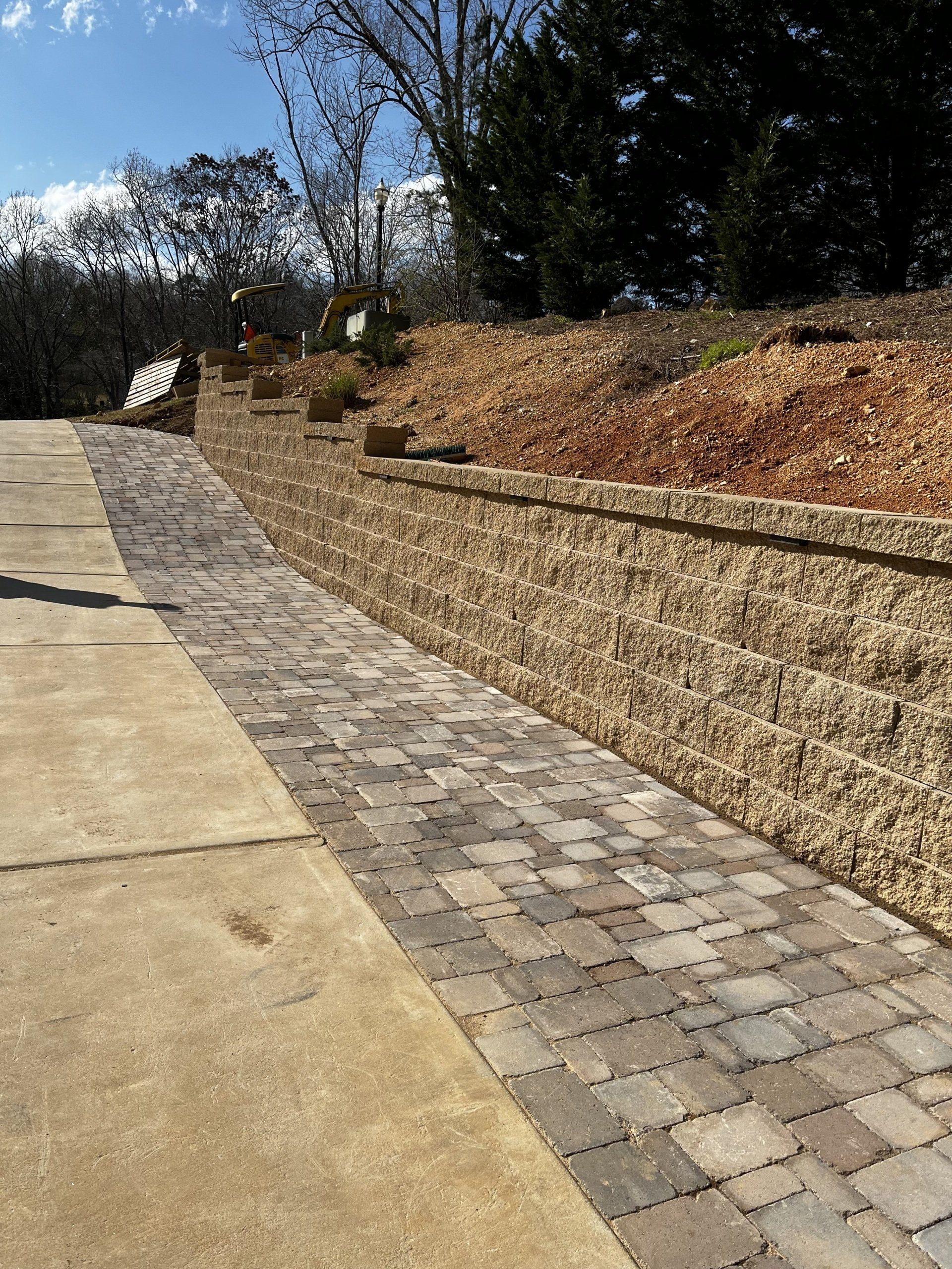 A brick walkway leading to a stone wall on a hillside.