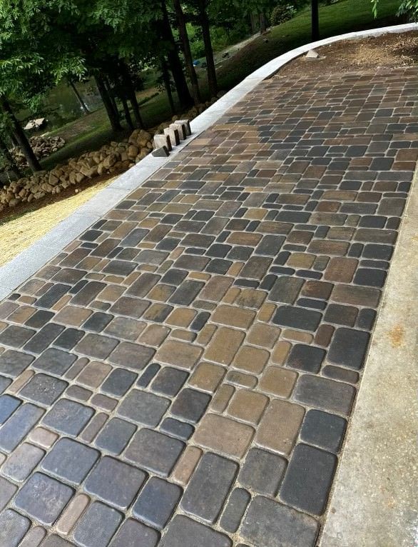 A brick driveway with trees in the background
