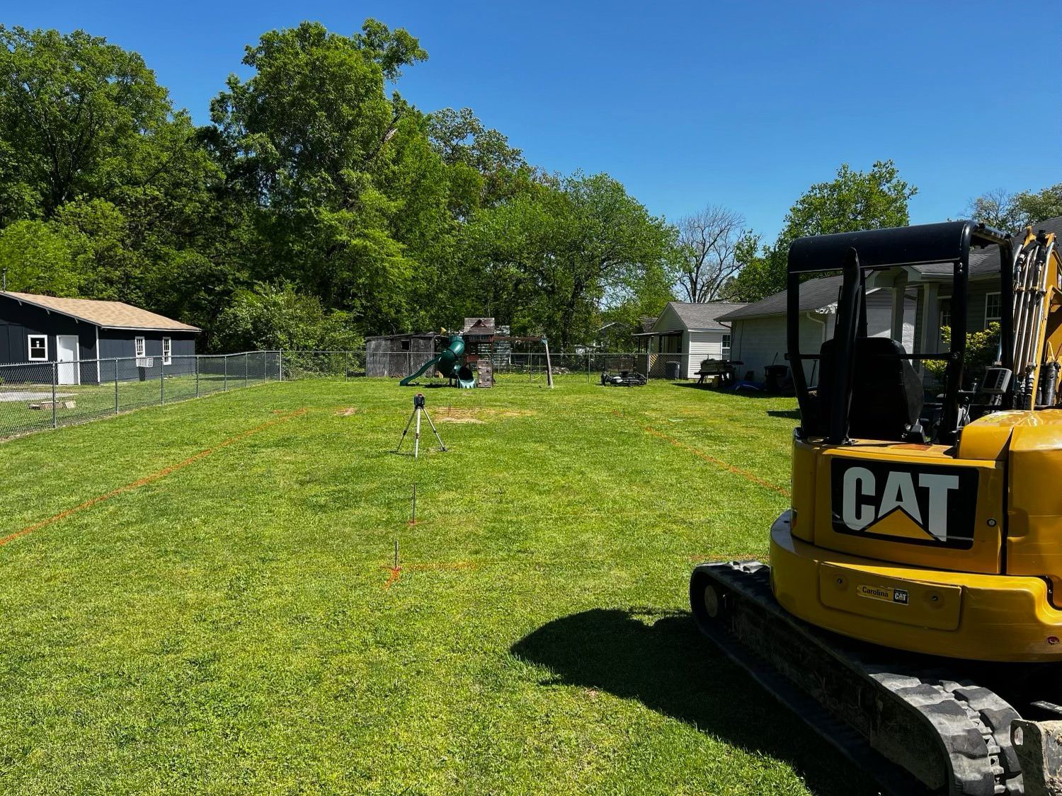 A yellow cat excavator is parked in a grassy field.