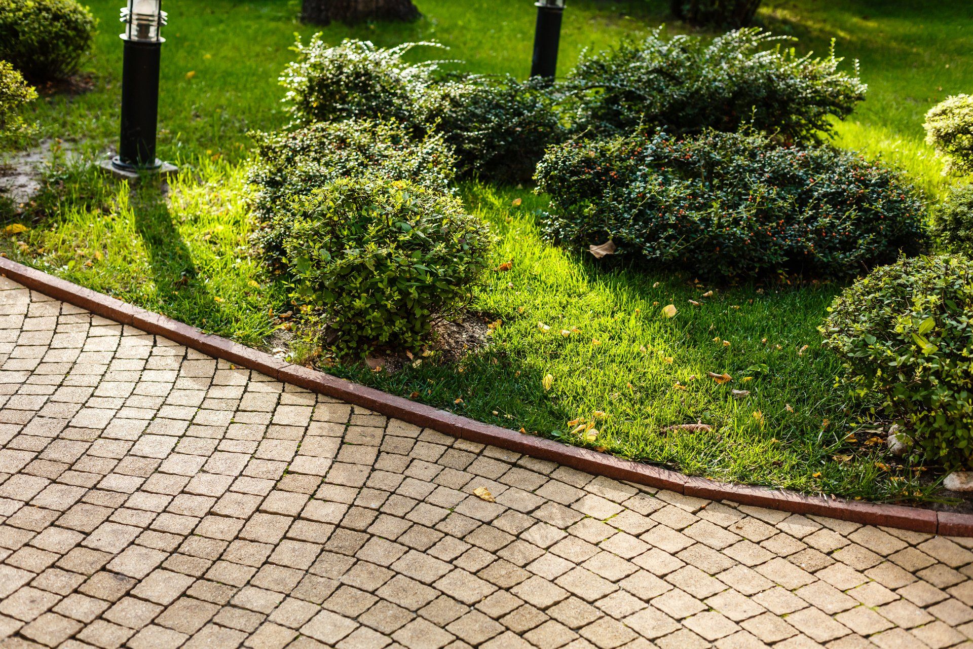 A brick walkway leading to a lush green garden.
