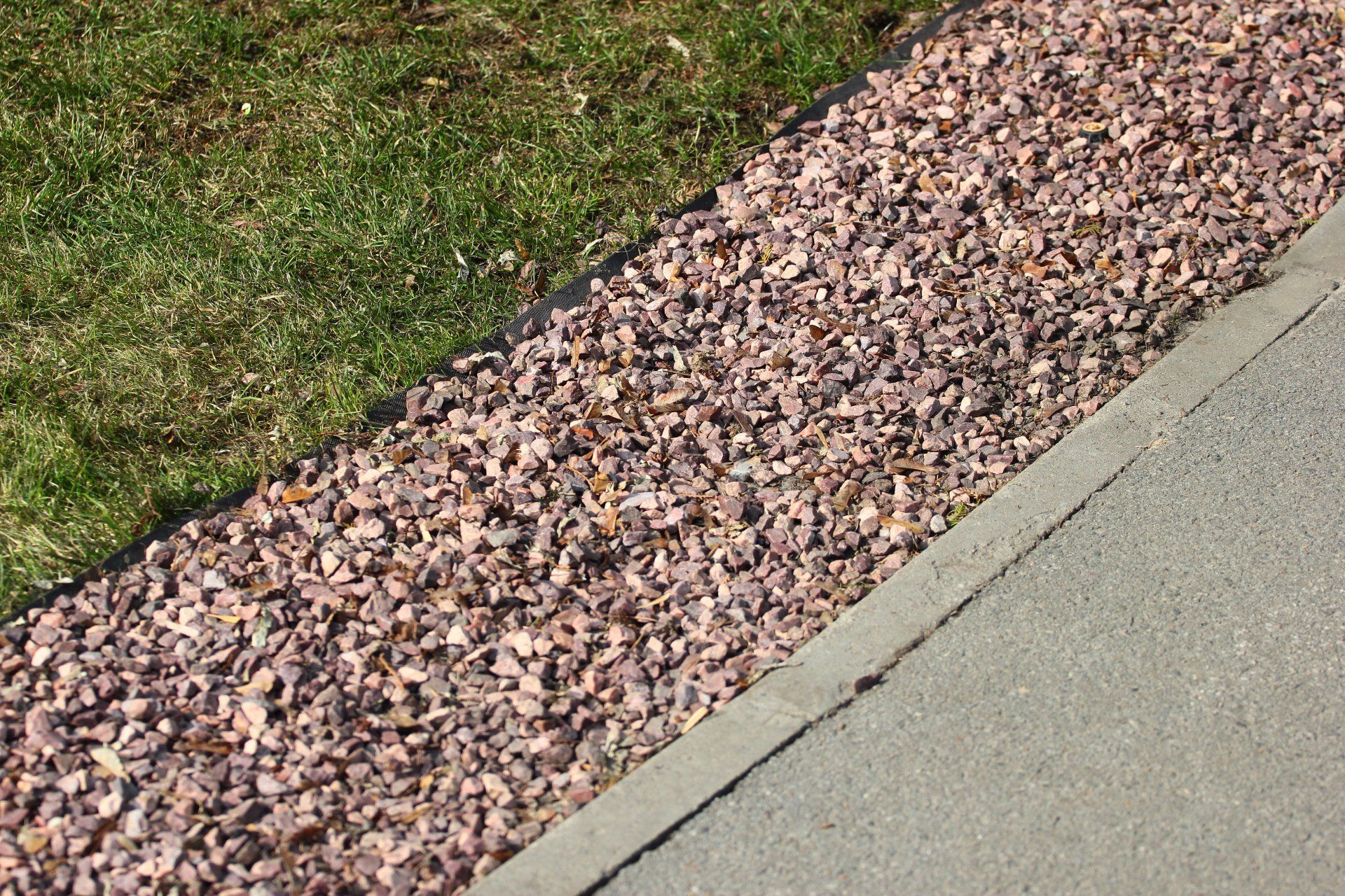 A sidewalk with gravel and grass on the side of it