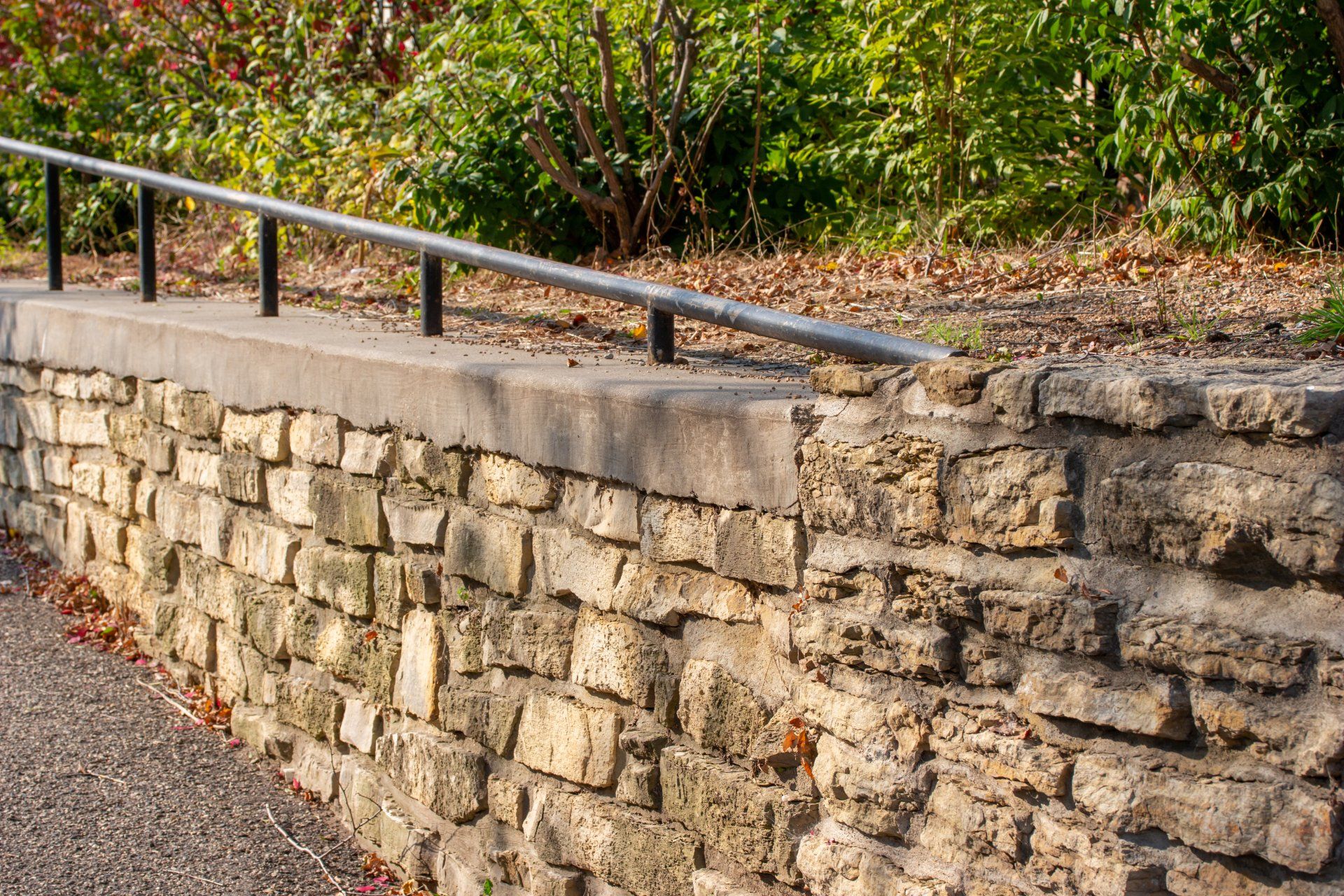 A stone wall with a metal railing on the side of it.