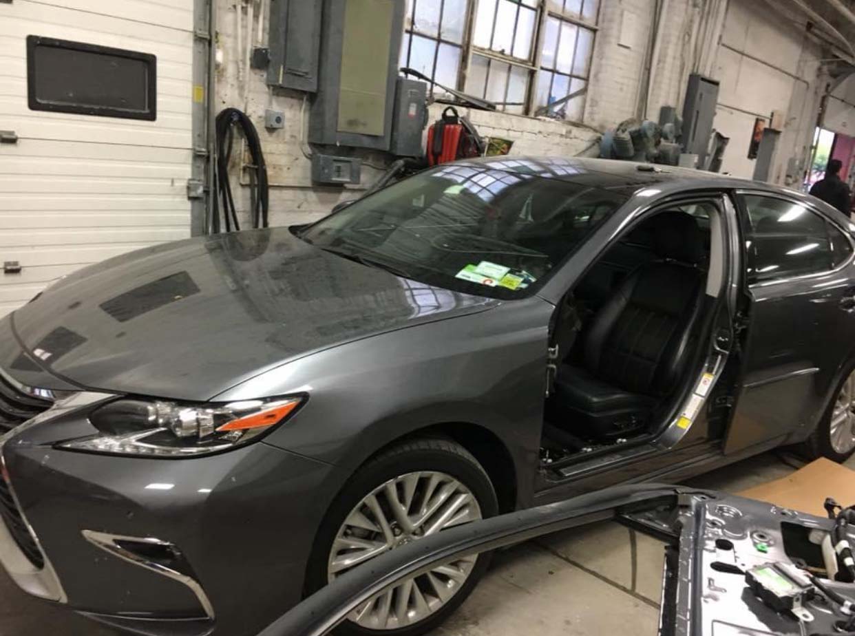 Gray sedan in a garage, front door open, with equipment and tools nearby.
