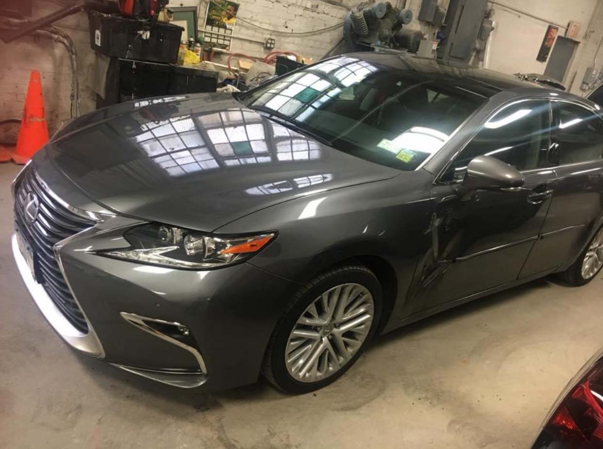 Dark gray sedan parked indoors in a garage, viewed from the front-left side.