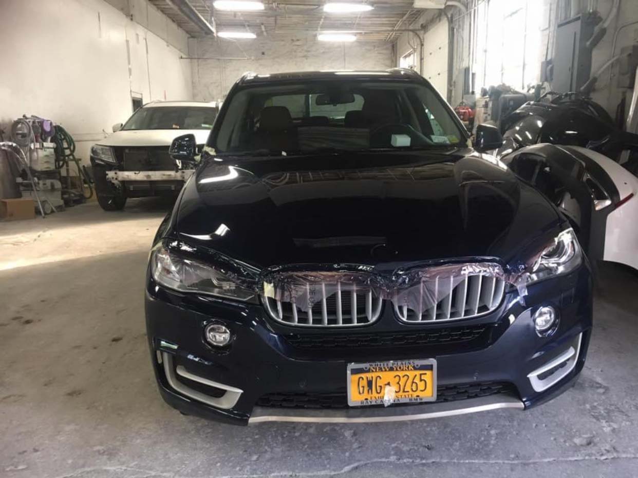 Dark blue SUV parked inside a garage, front view with yellow license plate