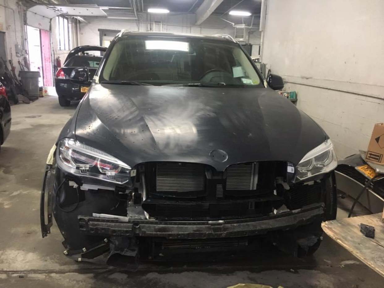 Black SUV with front-end damage parked in a garage