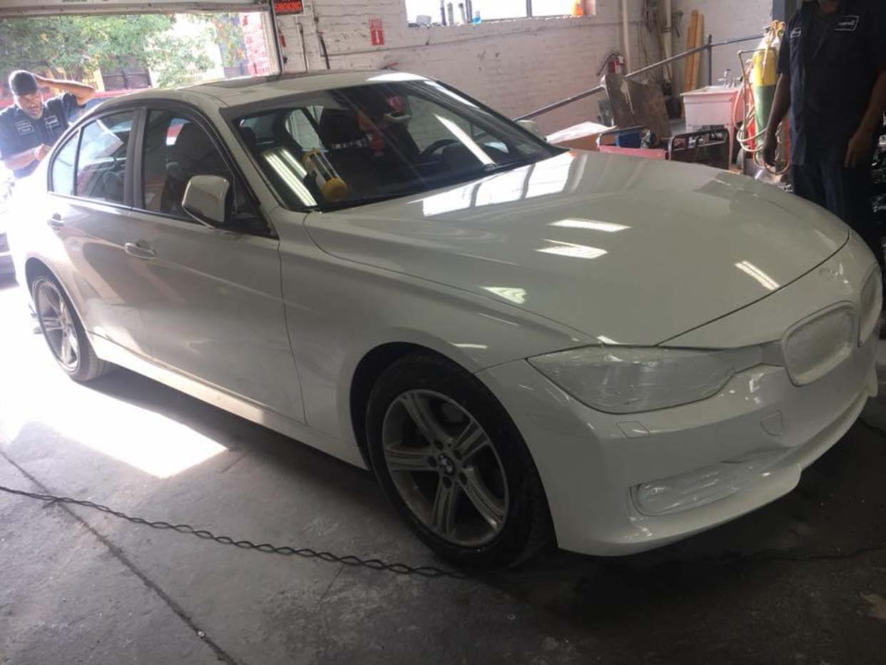 White sedan parked inside a garage with a person in the driver’s seat