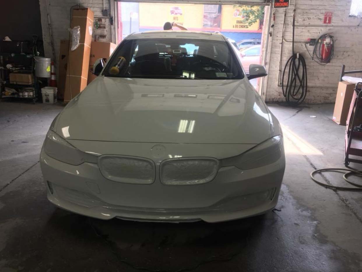 White BMW sedan parked inside a garage, viewed from the front.