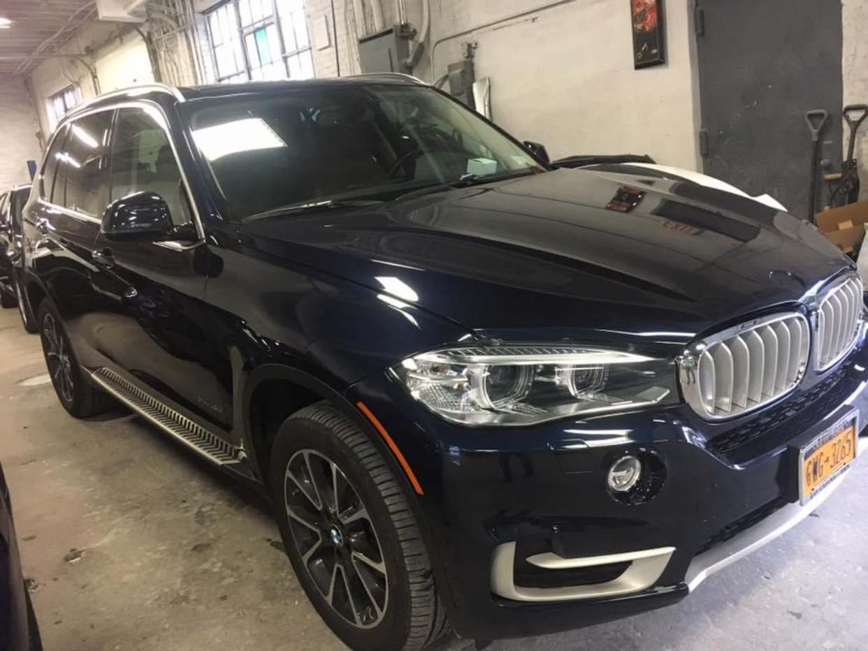 Dark blue BMW SUV parked indoors in a garage, front-left view
