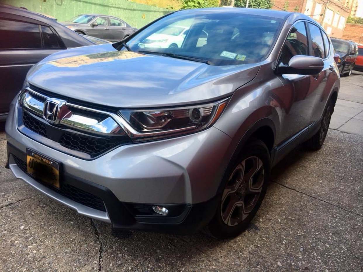Silver Honda CR-V parked on a wet street, front-left view with headlights visible