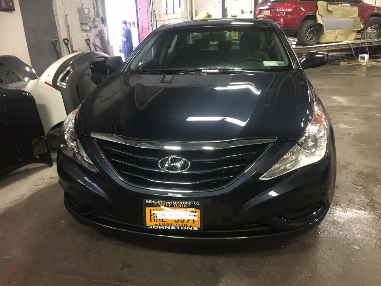 Black Hyundai sedan parked indoors in a garage, front view with headlights and grille visible