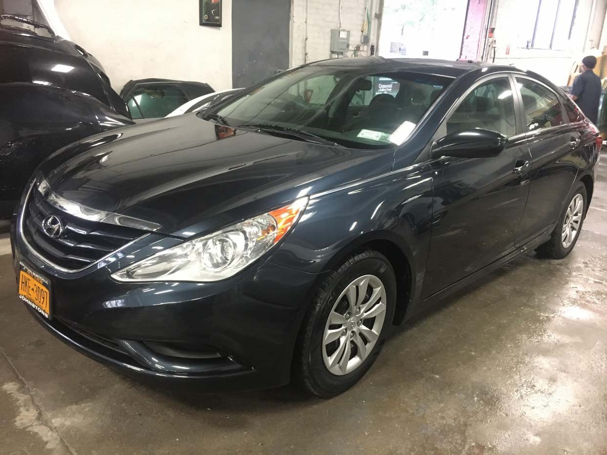 Black sedan parked indoors on a wet garage floor, front-left view