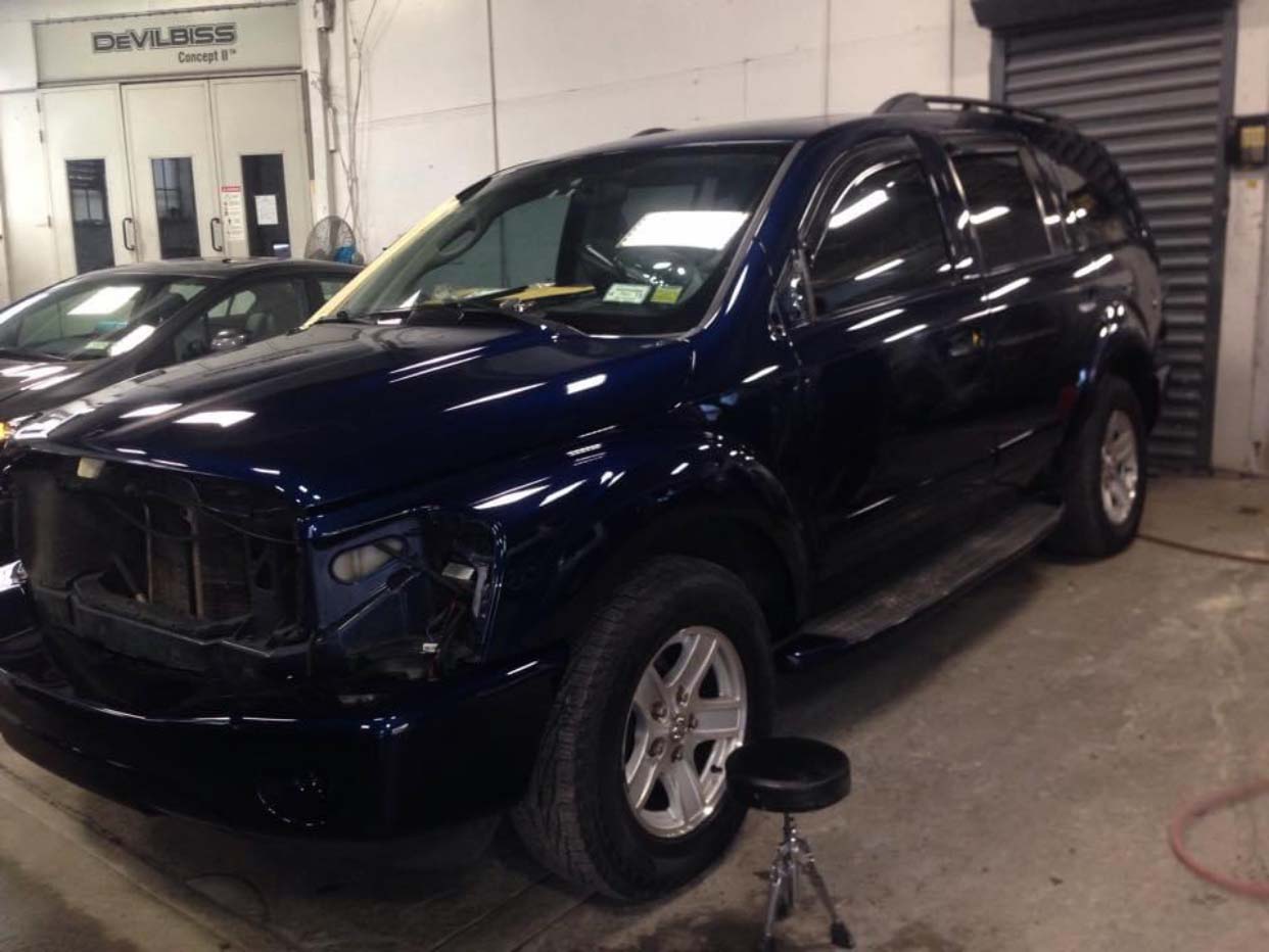 Dark blue SUV parked indoors in a garage or workshop with a bucket nearby