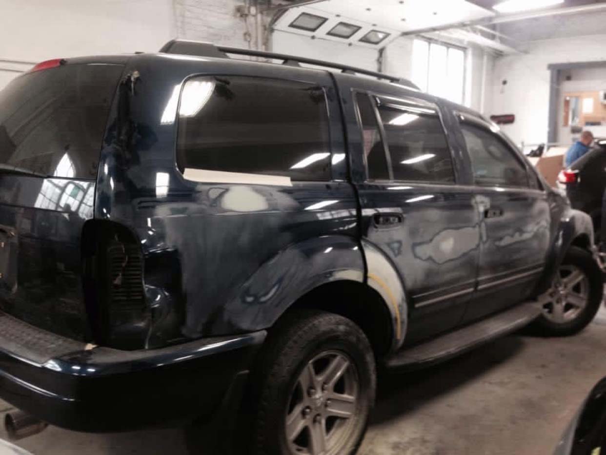 Black SUV parked inside an auto repair garage with a rear door open