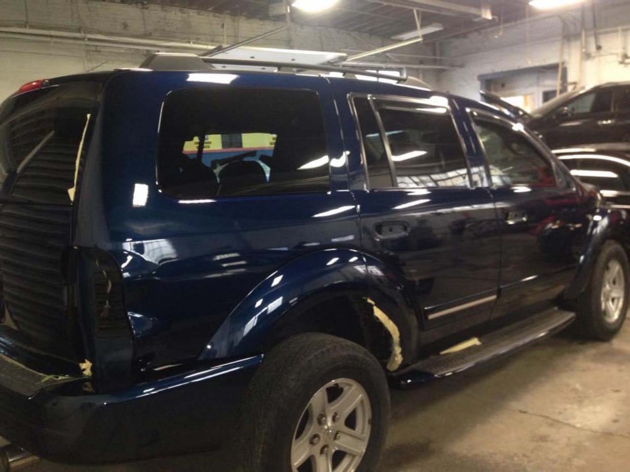 Dark blue SUV parked in an indoor garage, viewed from the side.