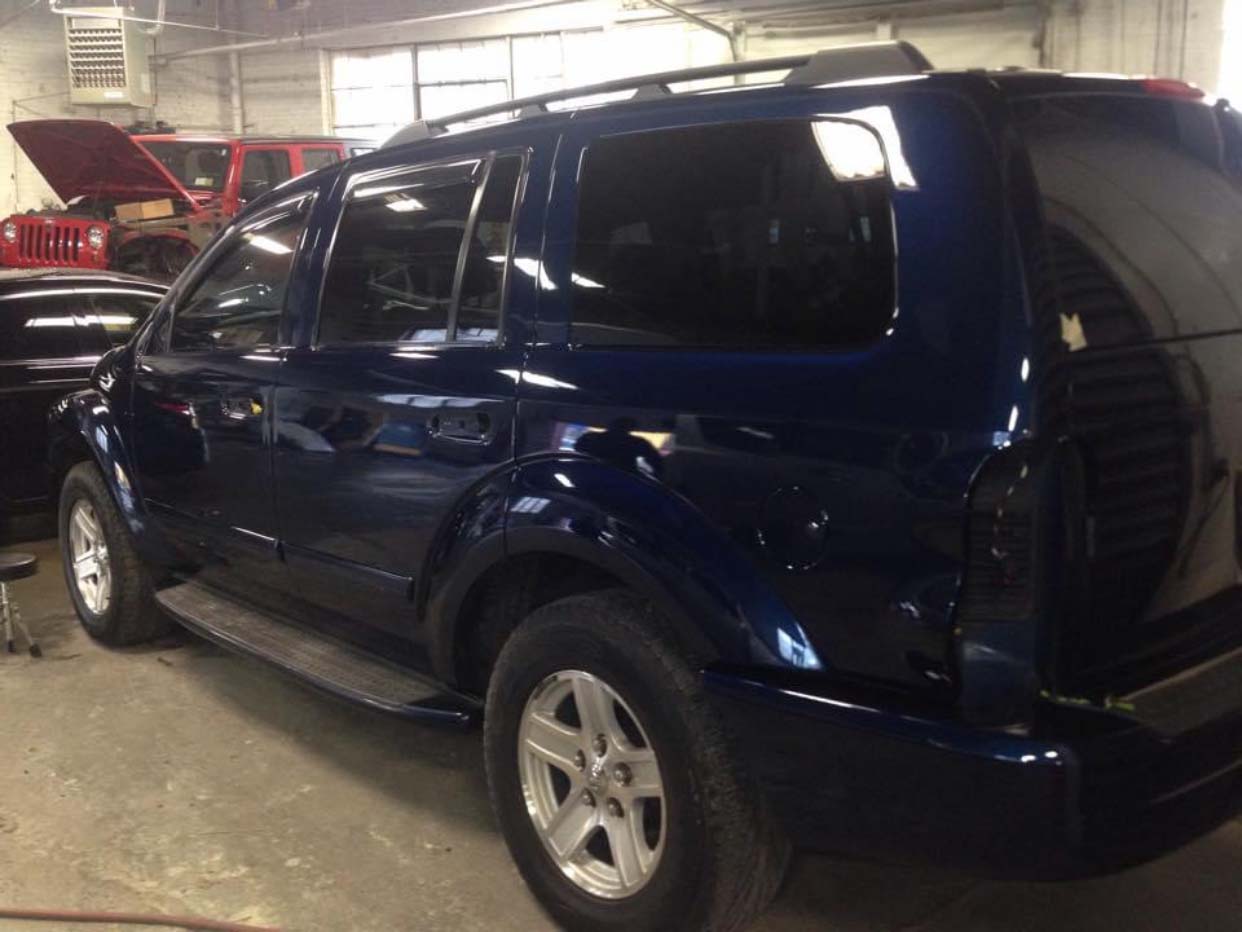 Dark blue SUV parked in a garage, side view with rear hatch visible