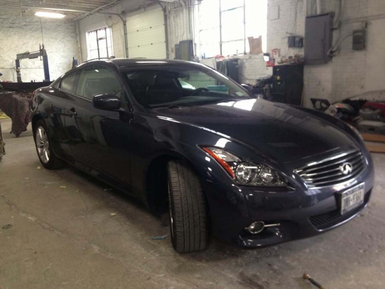 Dark blue sedan parked inside a garage, viewed from the front-left side.