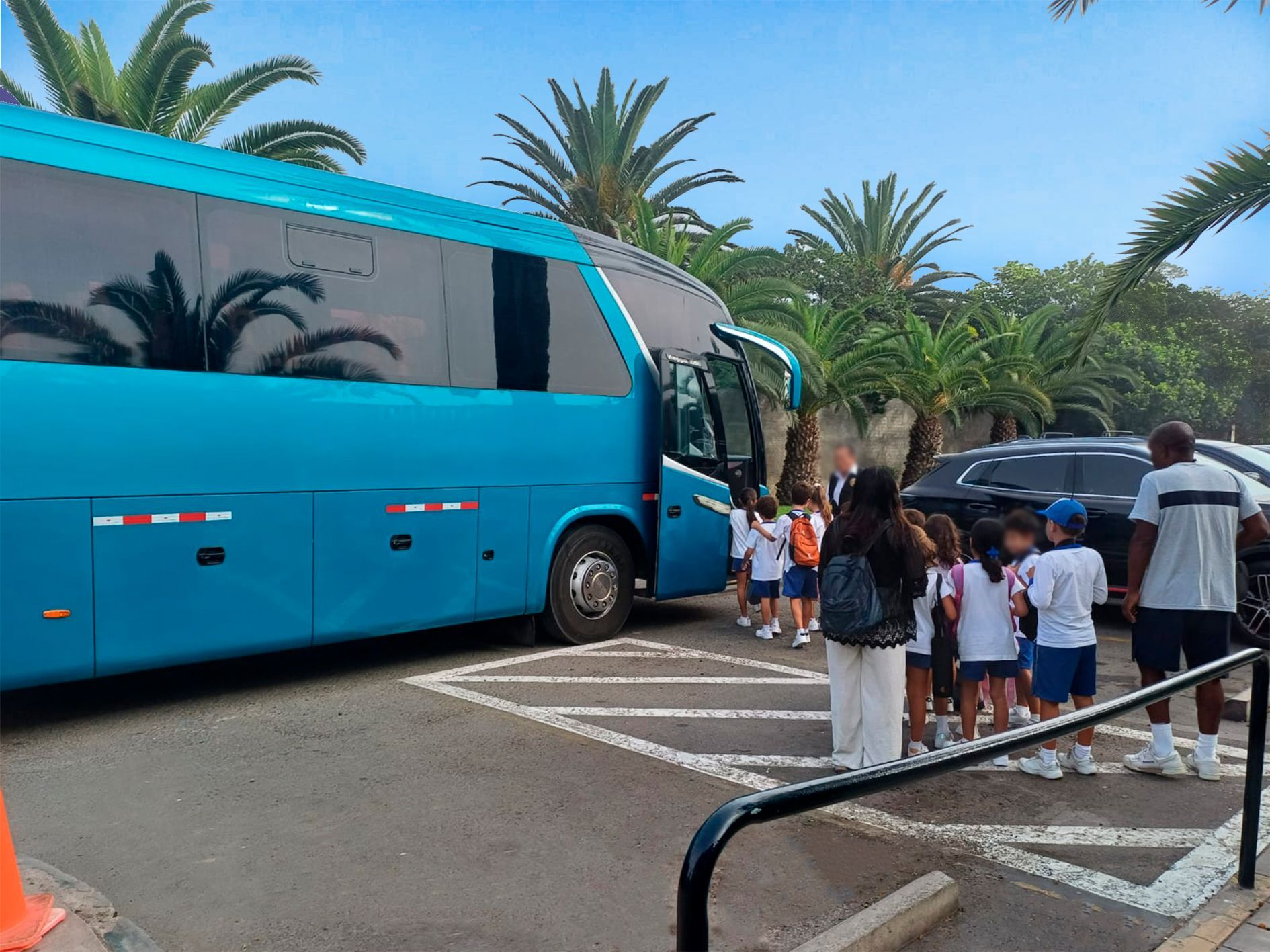 Un grupo de niños están parados frente a un autobús azul.