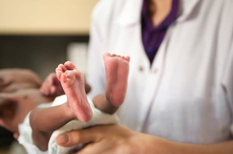 Doctor holding a newborn baby’s feet during a medical exam