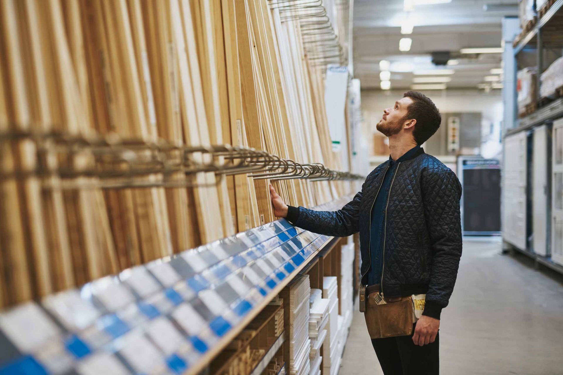 Man browsing wood samples in a bright showroom aisle