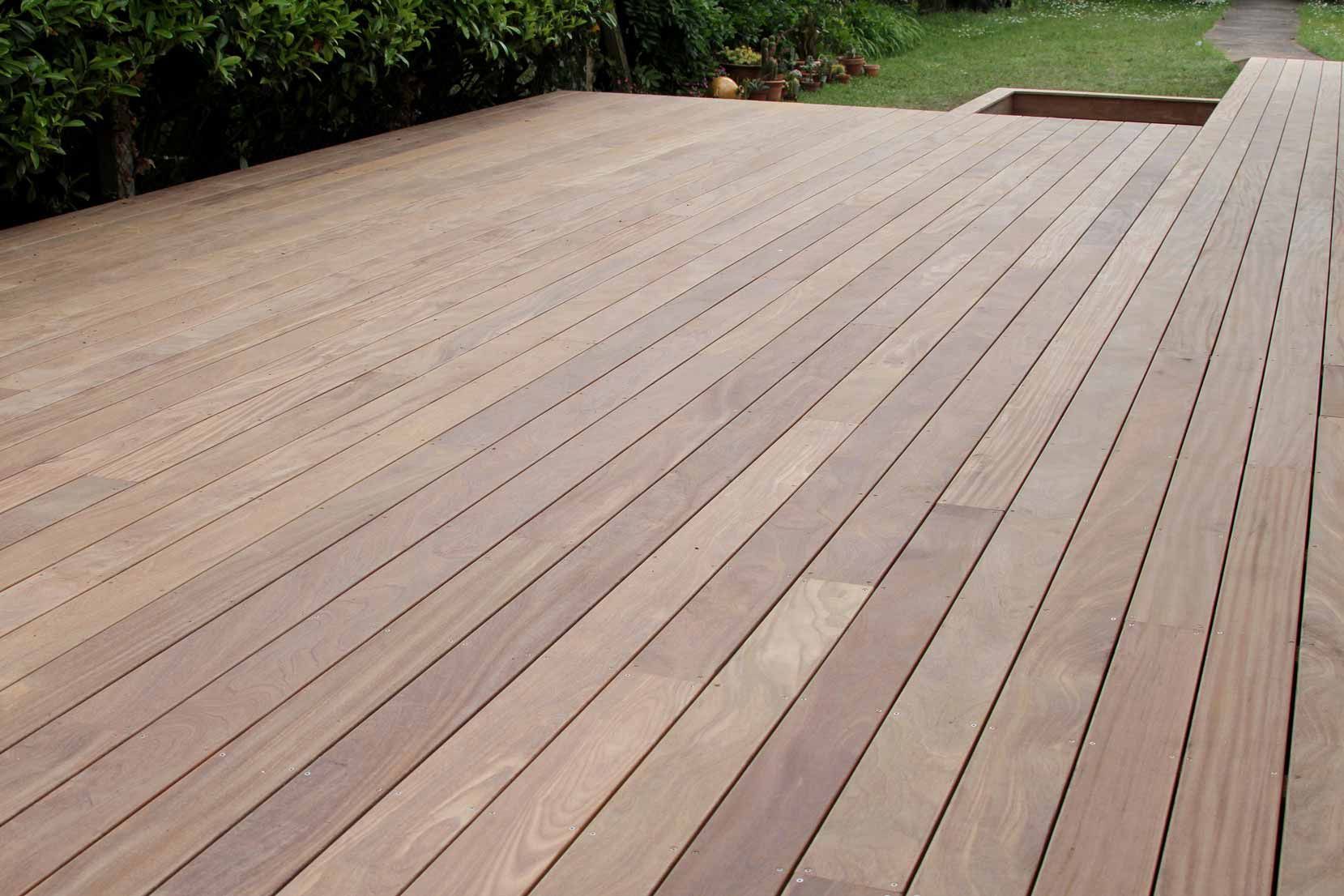 Wide wooden deck with light brown planks beside a grassy yard