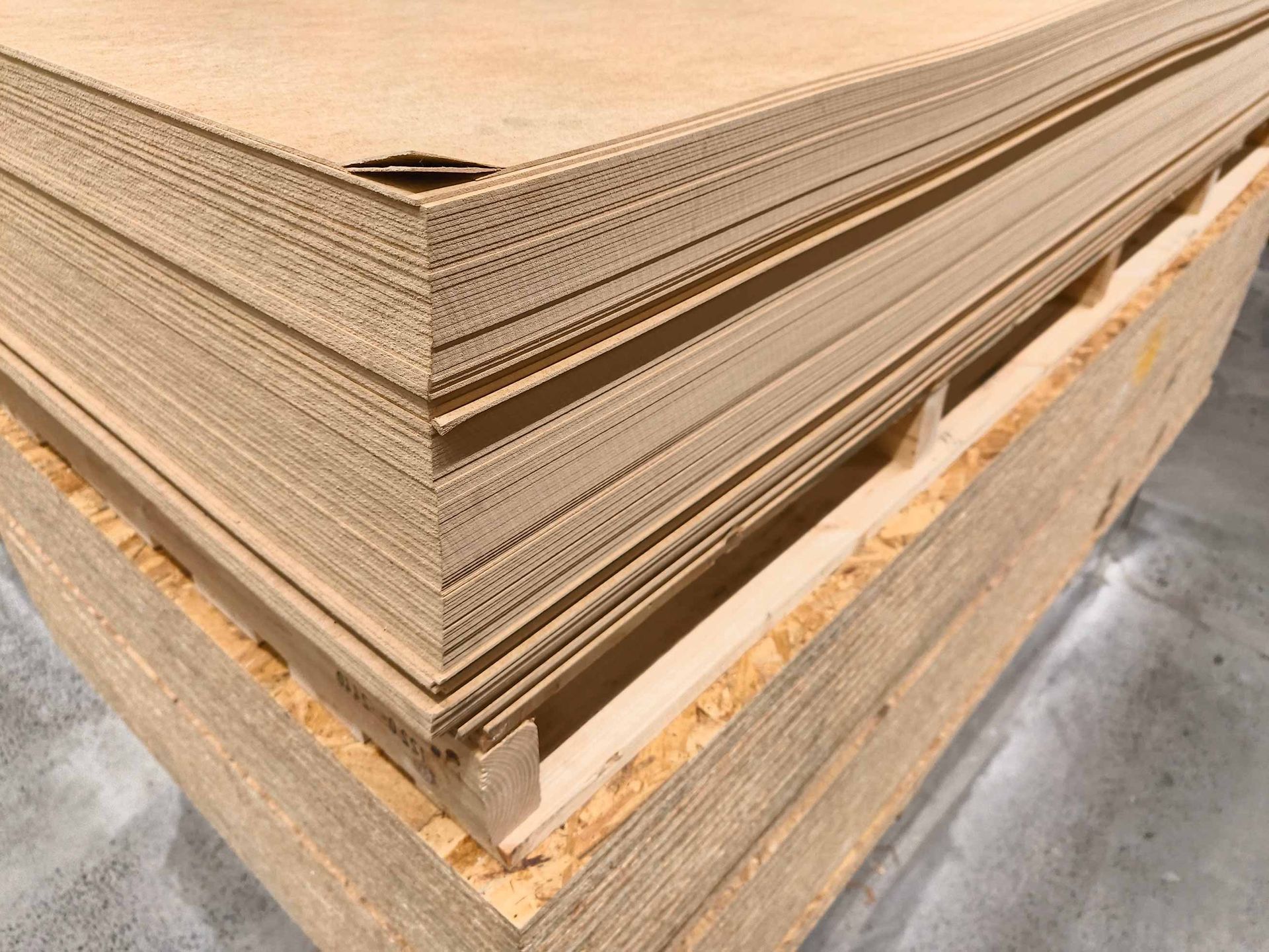 Stacked corrugated cardboard sheets on a pallet in a warehouse setting