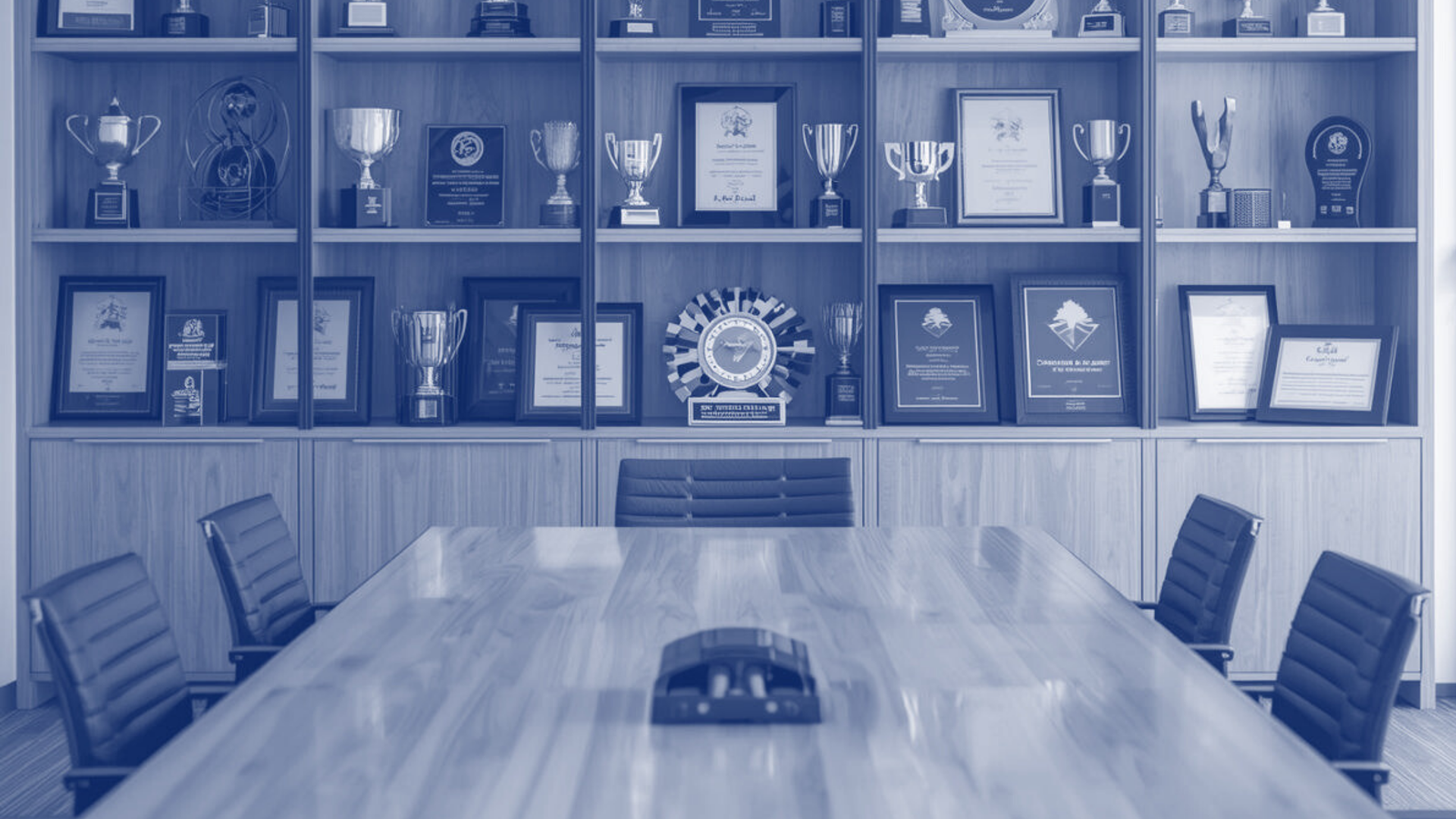 Conference room with awards on shelves, a large table, and chairs.