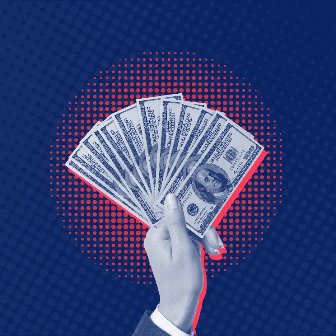 A person is holding a fan of money in their hand.