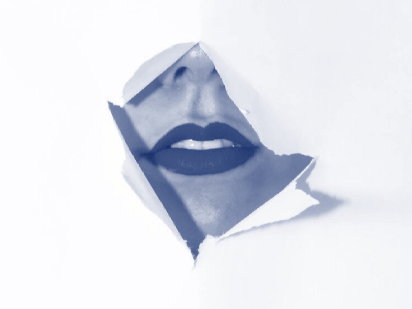 A woman 's face is visible through a hole in a piece of paper.