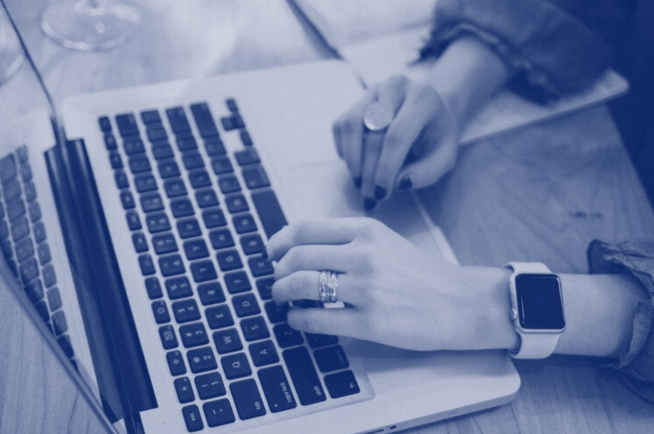A woman wearing a watch is typing on a laptop computer.