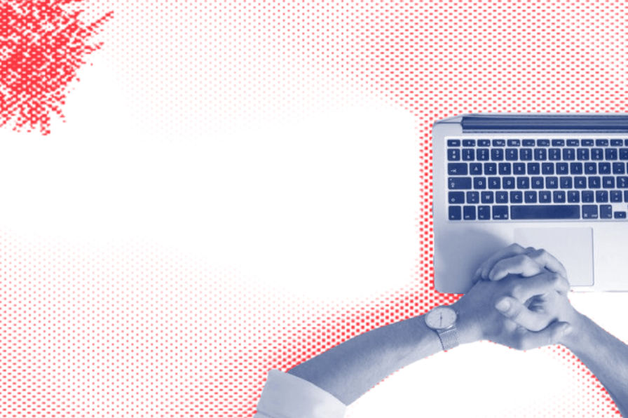 A person is holding hands in front of a laptop computer.