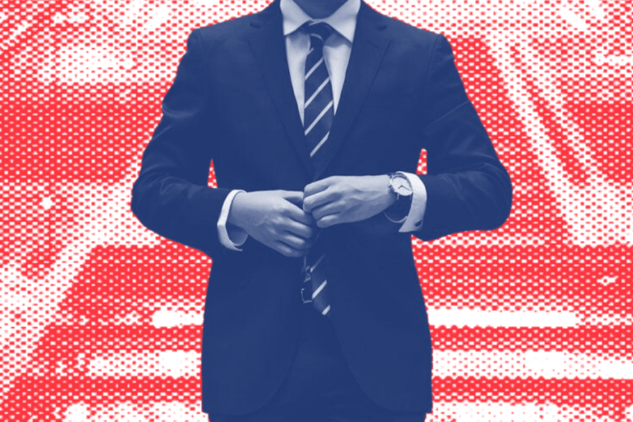 A man in a suit and tie is standing in front of an american flag.