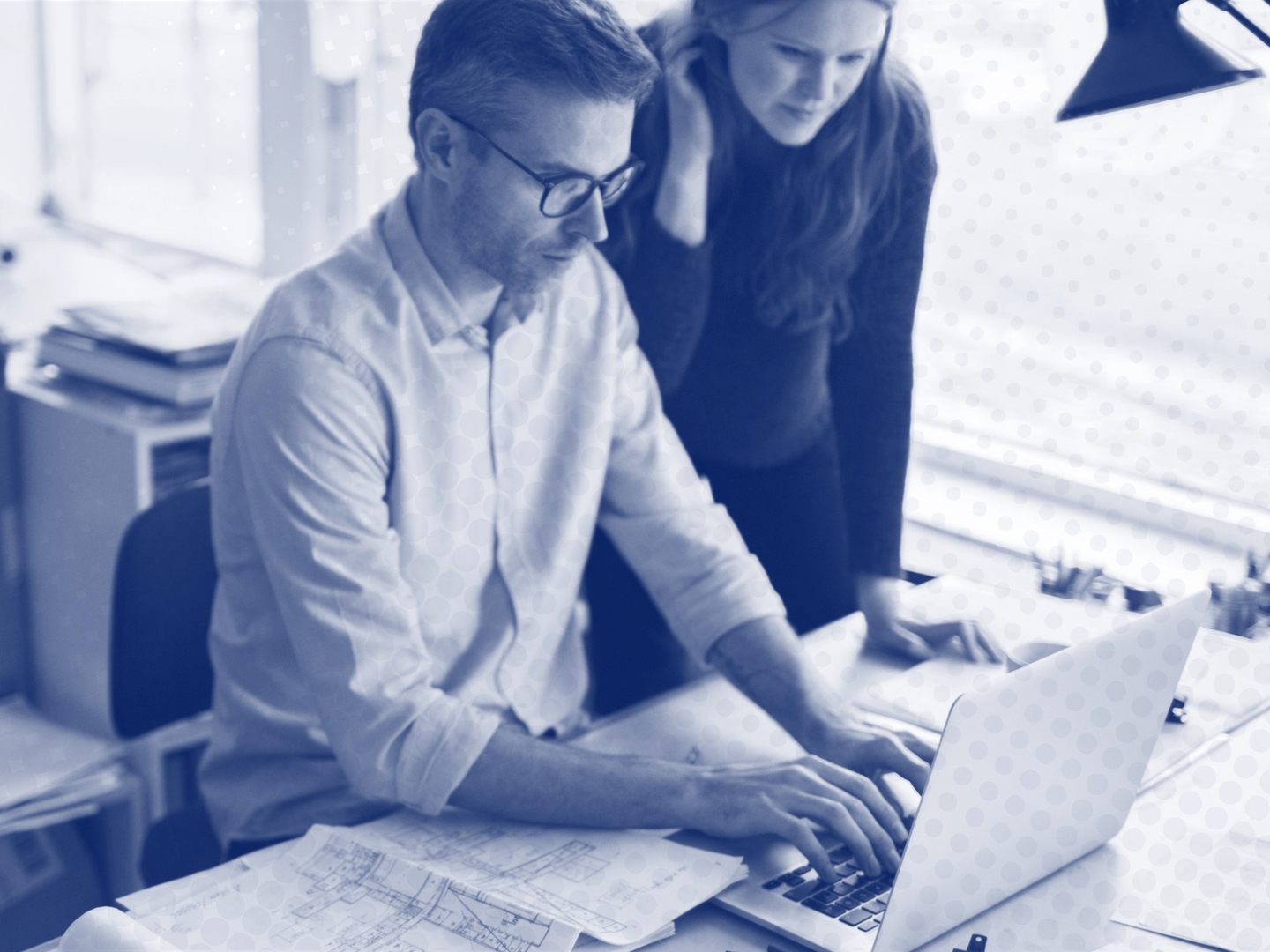 A man and a woman are looking at a laptop computer.