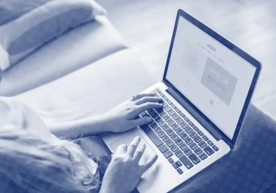 A person is typing on a laptop computer while sitting on a couch.