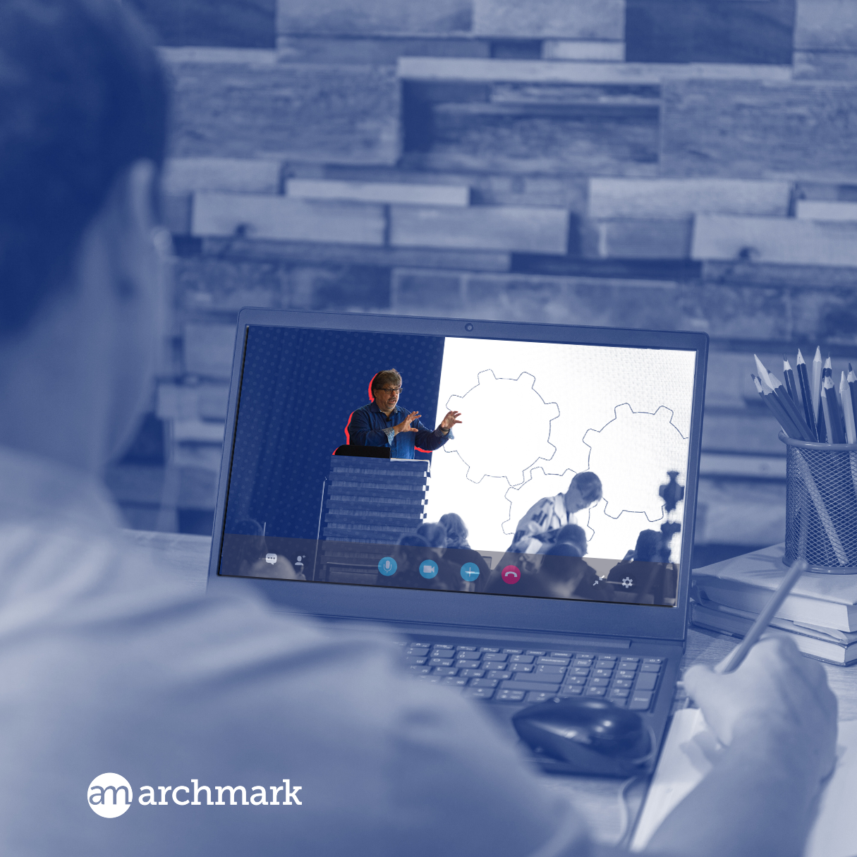 A man is sitting in front of a laptop that says archmark