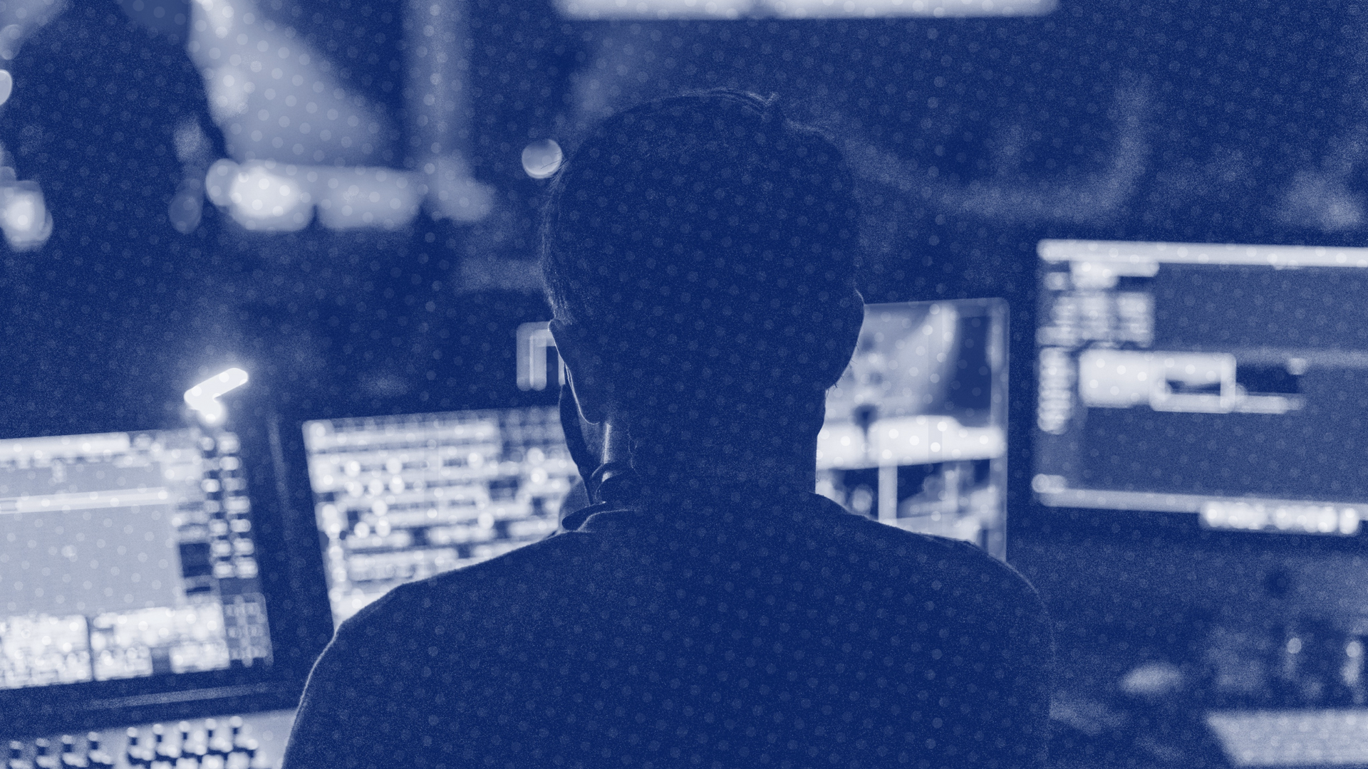 a man wearing a headset is sitting in front of a computer screen .