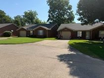 Suburban homes with a wide driveway and green lawns on a sunny day
