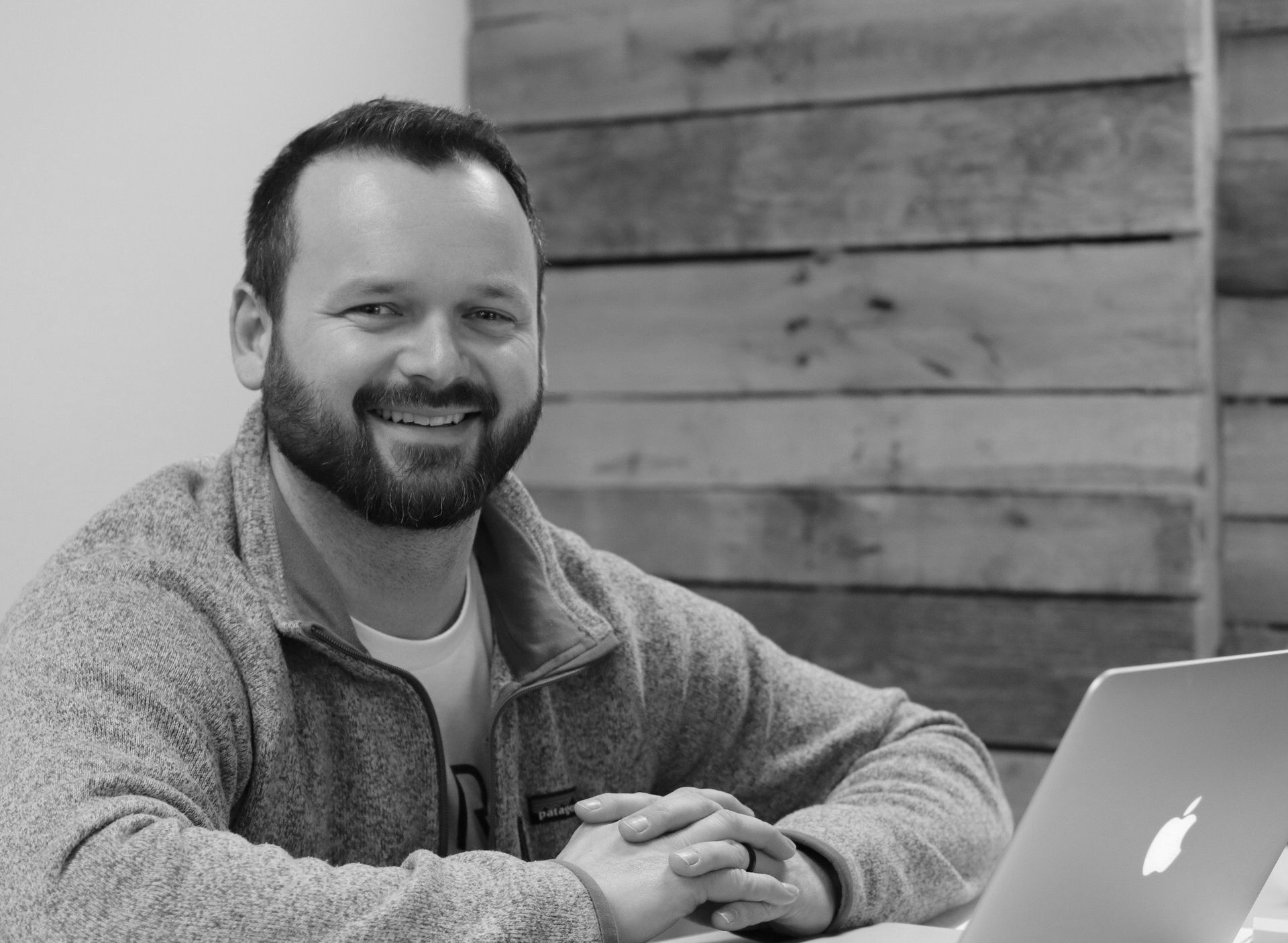 A man with a beard is sitting in front of a laptop computer.