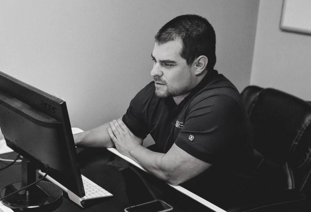 A man is sitting at a desk looking at a computer screen.