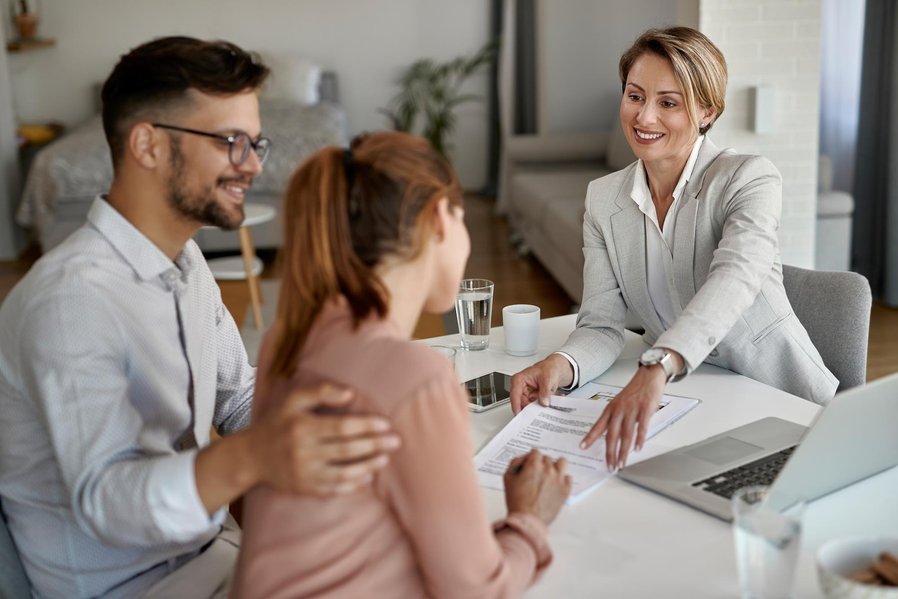 A man and a woman are sitting at a table talking to a real estate agent.