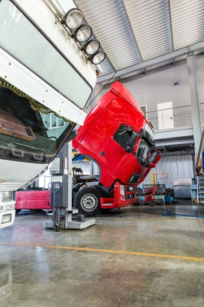A Red Truck is Sitting on a Lift in a Garage With Its Hood Up — Wards Byron Shire Truck & Machinery Centre In Tyagarah, NSW