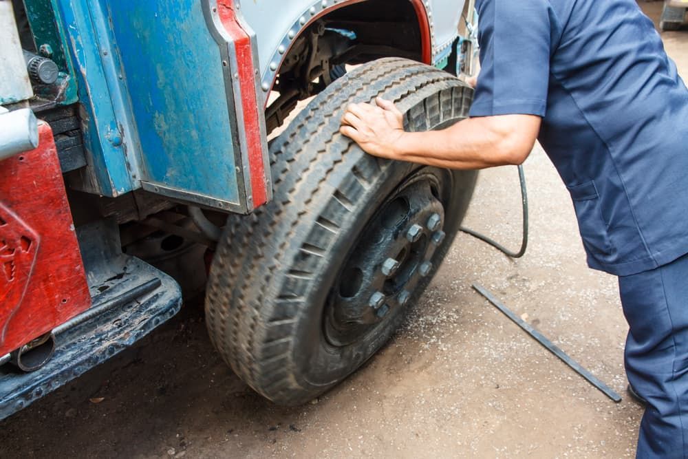A Man is Changing a Tire on a Truck — Wards Byron Shire Truck & Machinery Centre In Tyagarah, NSW