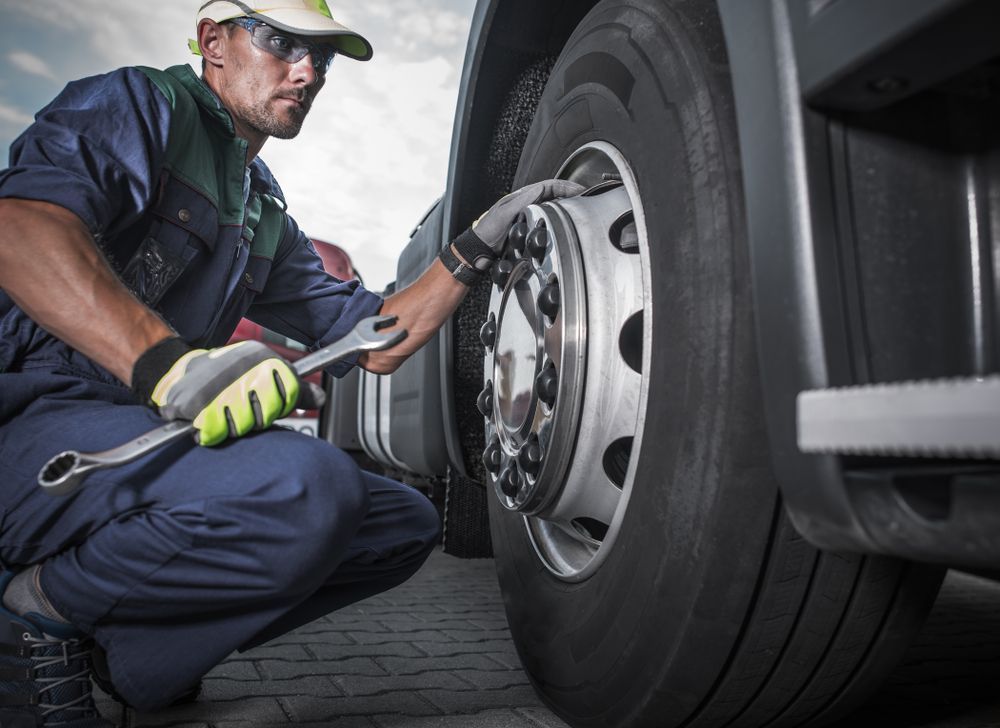 A Man Is Working On A Truck Tyre With A Wrench — Wards Byron Shire Truck & Machinery Centre In Tyagarah, NSW