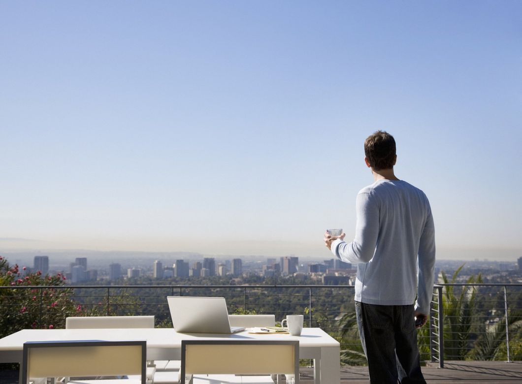 man holding drink looking at LA skyline
