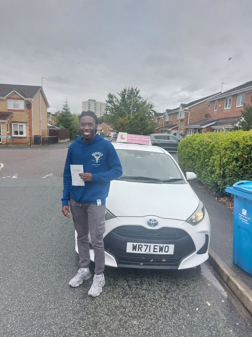 Man holding paperwork stands in front of a white car with an