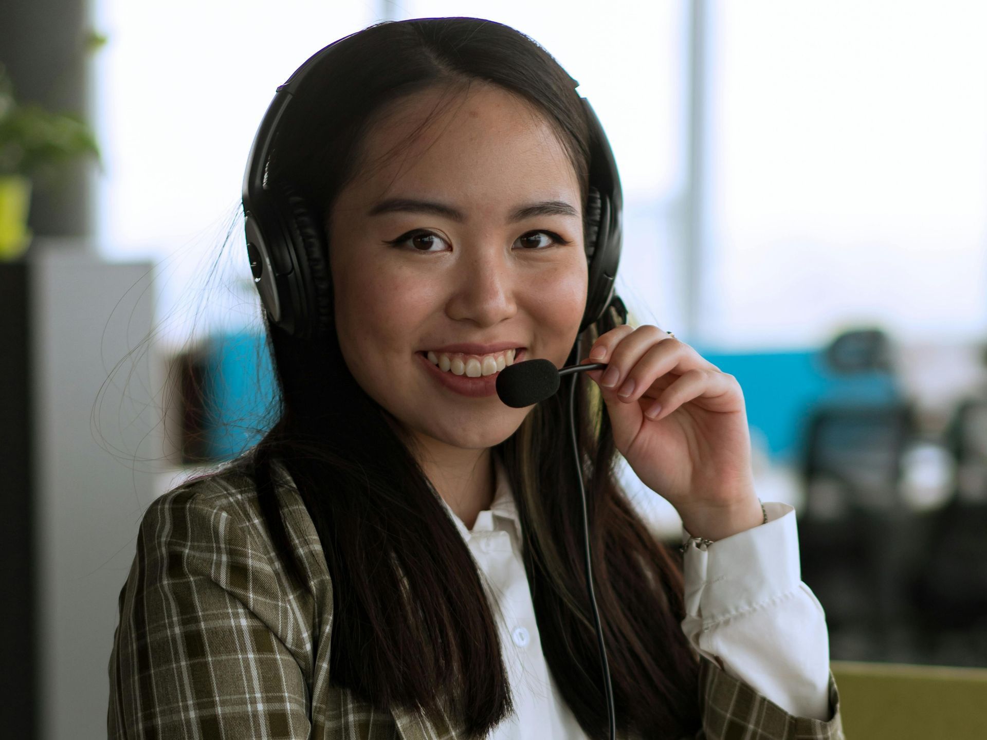 A woman wearing headphones and a microphone is smiling at the camera.