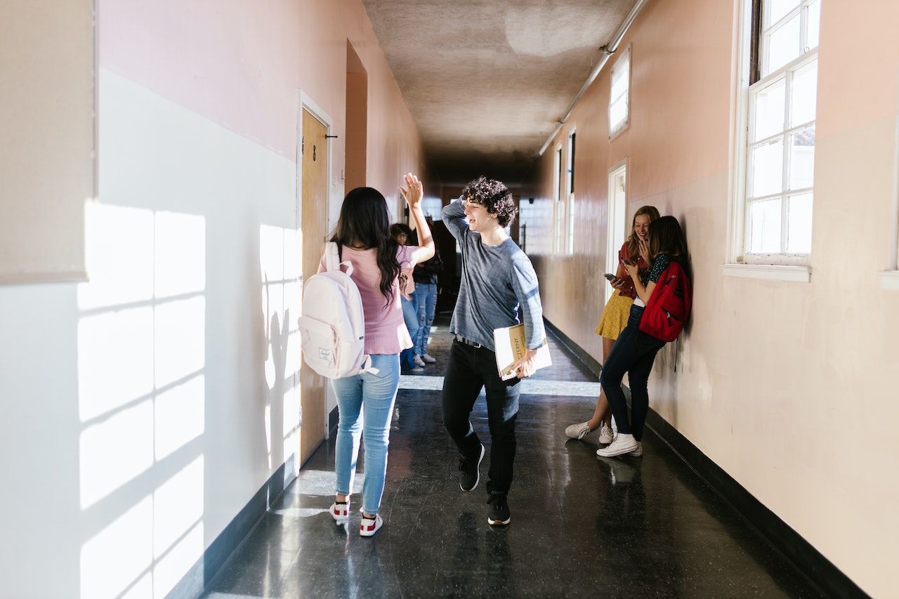 A group of students are walking down a hallway in a school.
