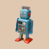 A blue toy robot with red feet is standing on a beige background.