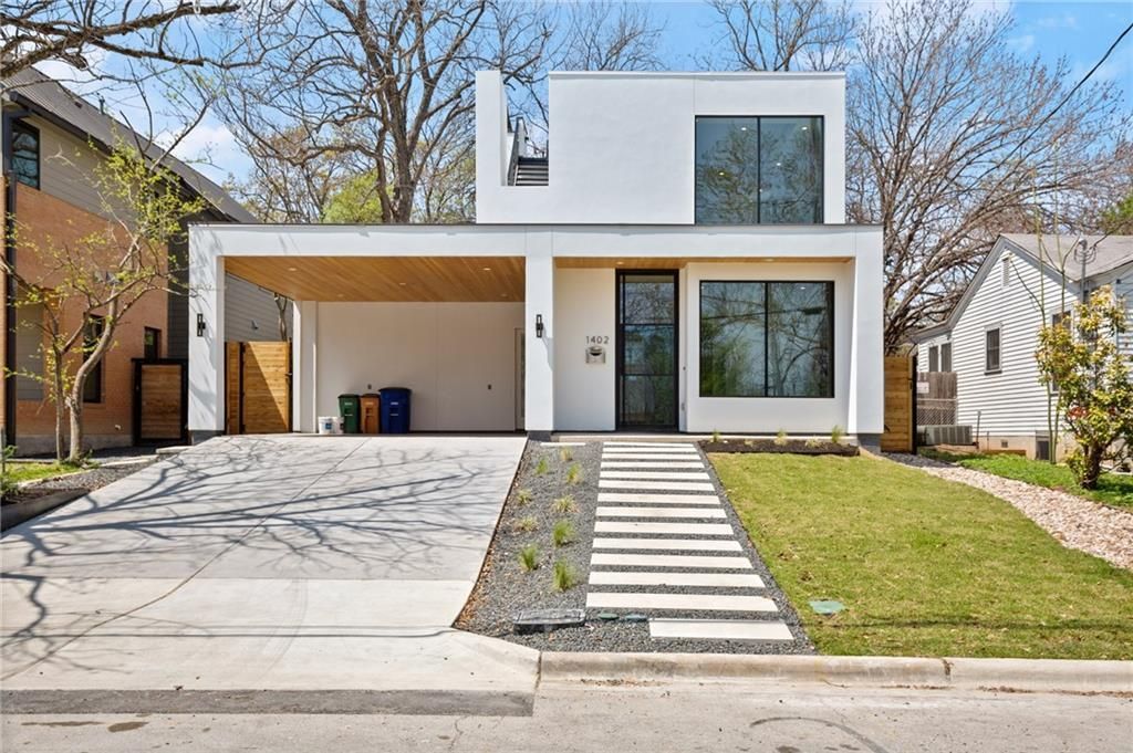 a modern white house with a concrete walkway leading to it .