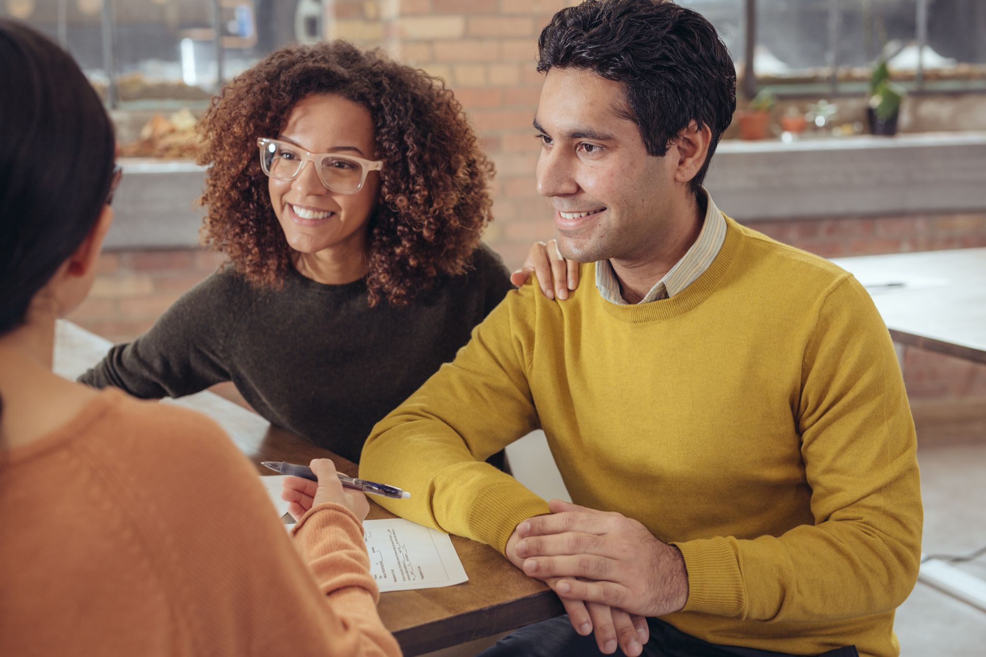 a man and a woman are sitting at a table talking to a woman .